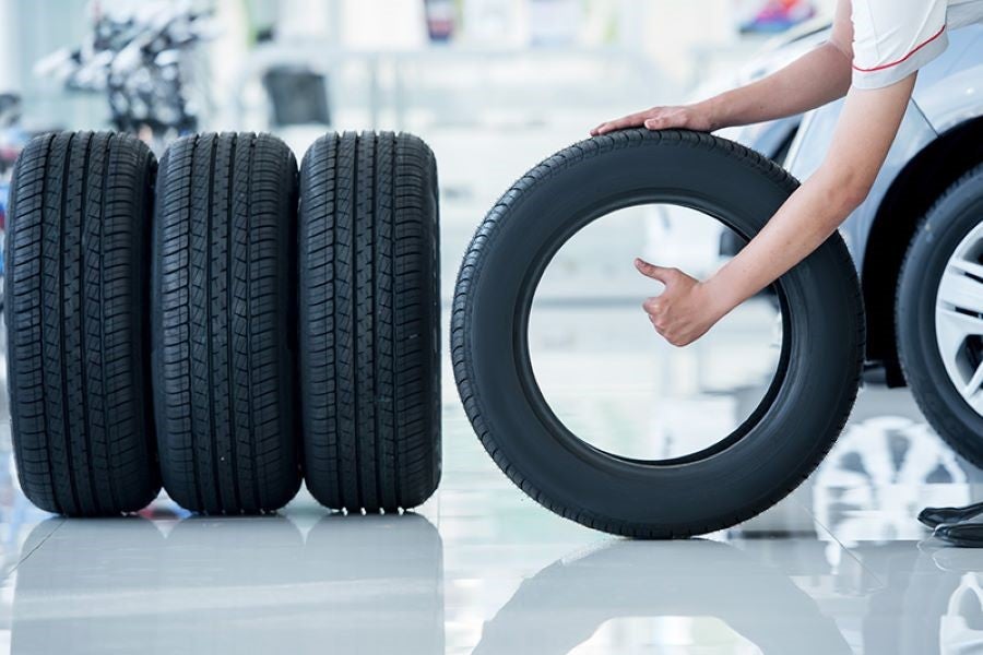 Hand showing thumbs up near a stack of new tires